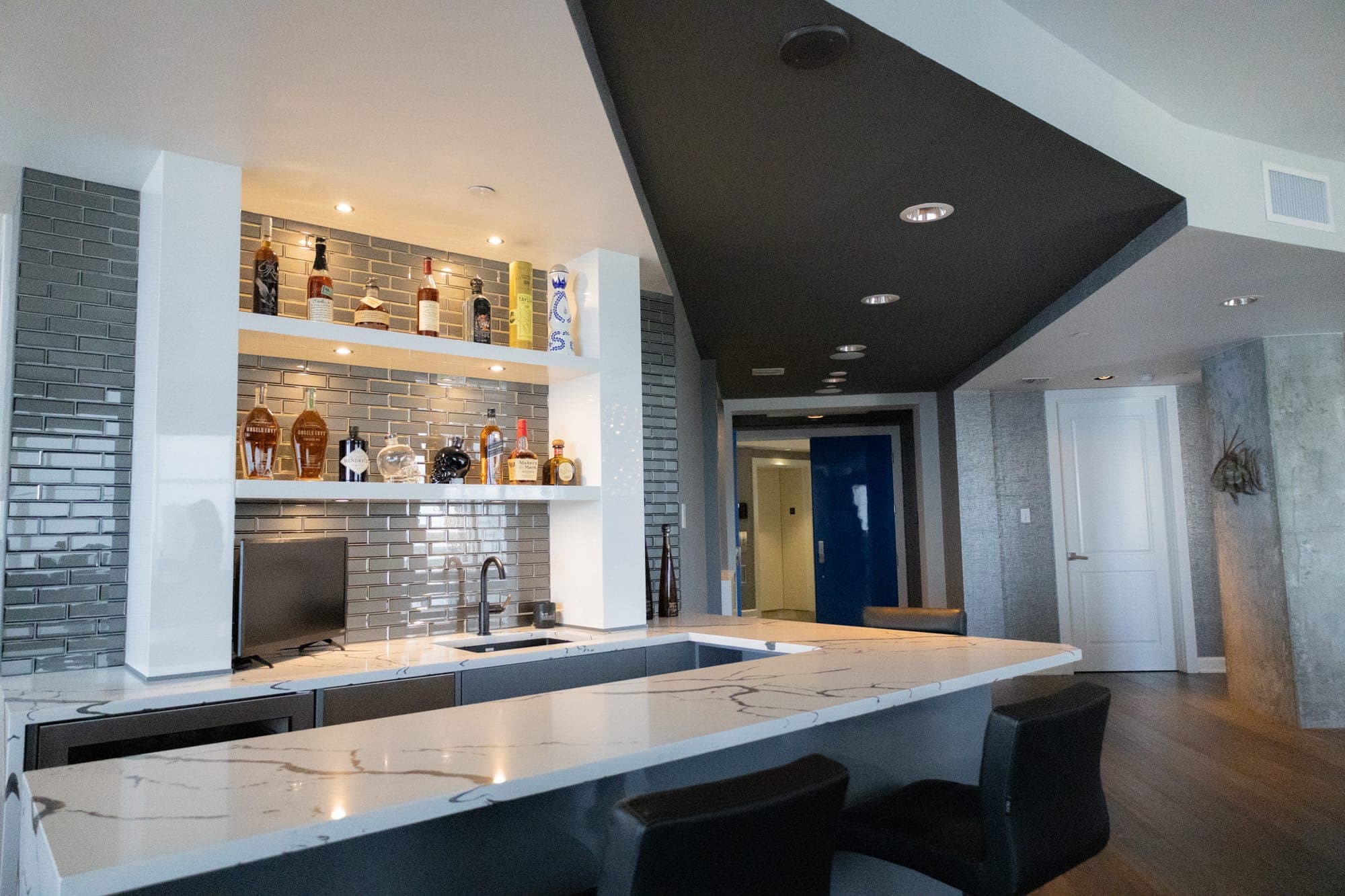 Custom wet bar with quartz countertop and subway tile backsplash in a high-rise condo remodel