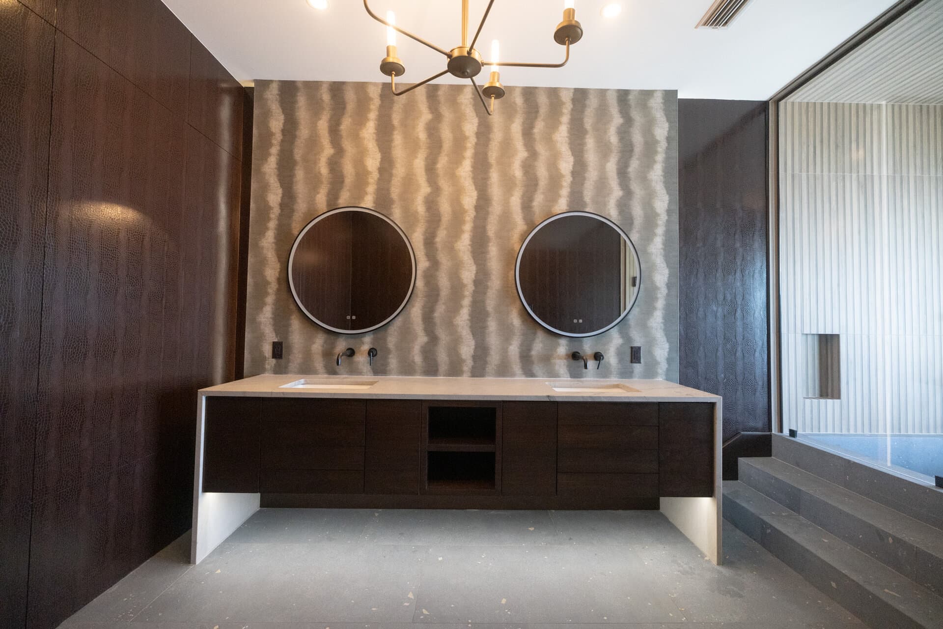 Dark luxury master bathroom with textured walls and brass chandelier