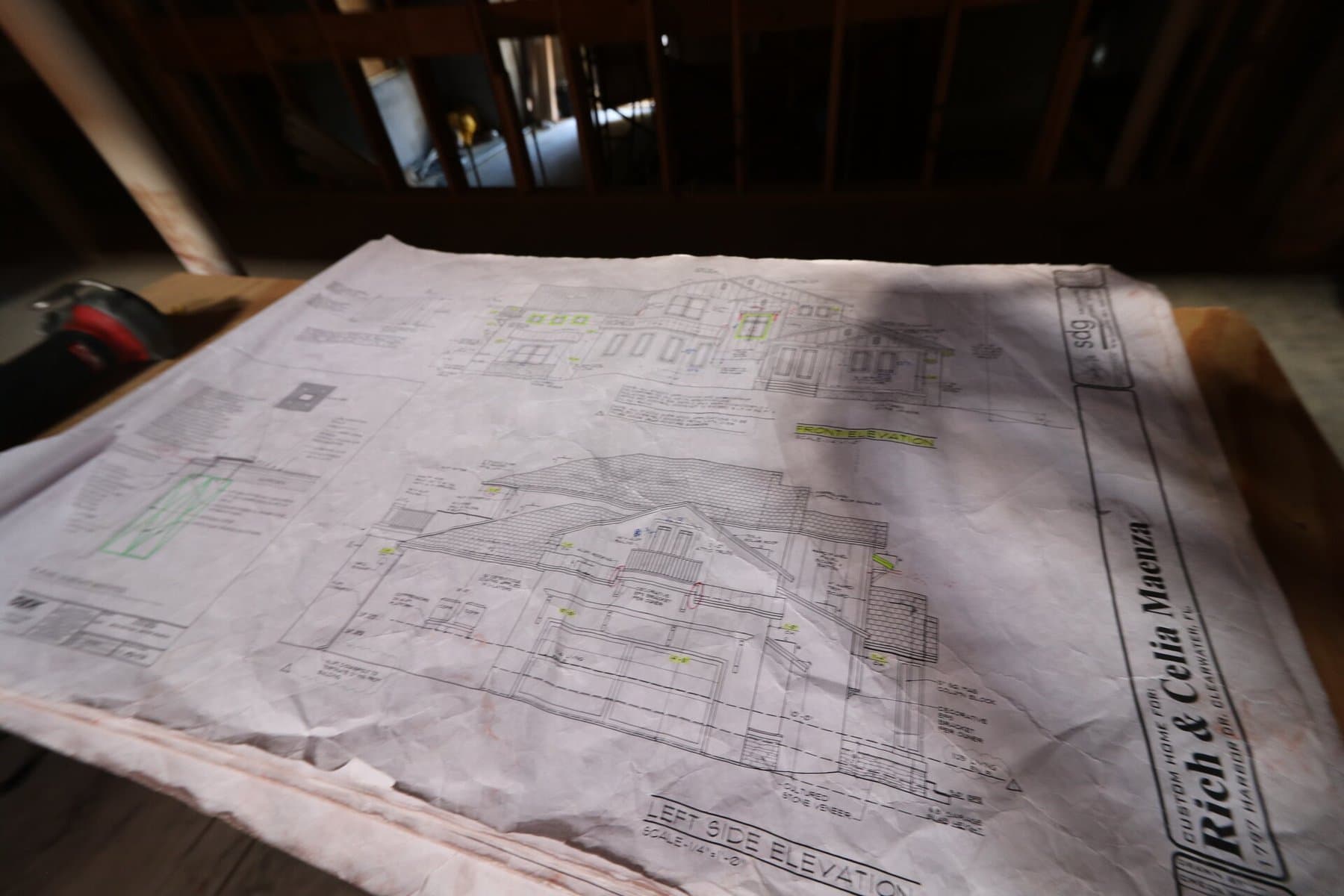 Real blueprints spread out on workbench with framing visible behind